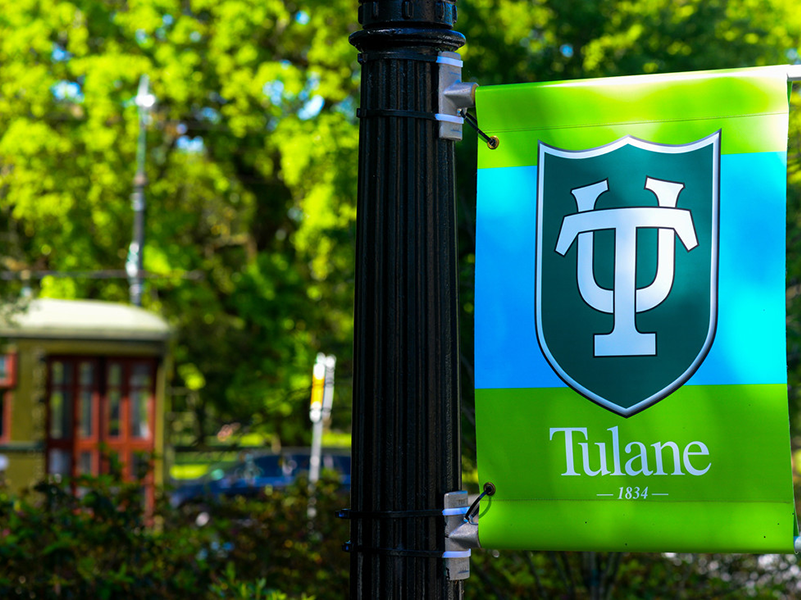 Tulane banner in front of university with streetcar passing by on St. Charles Ave