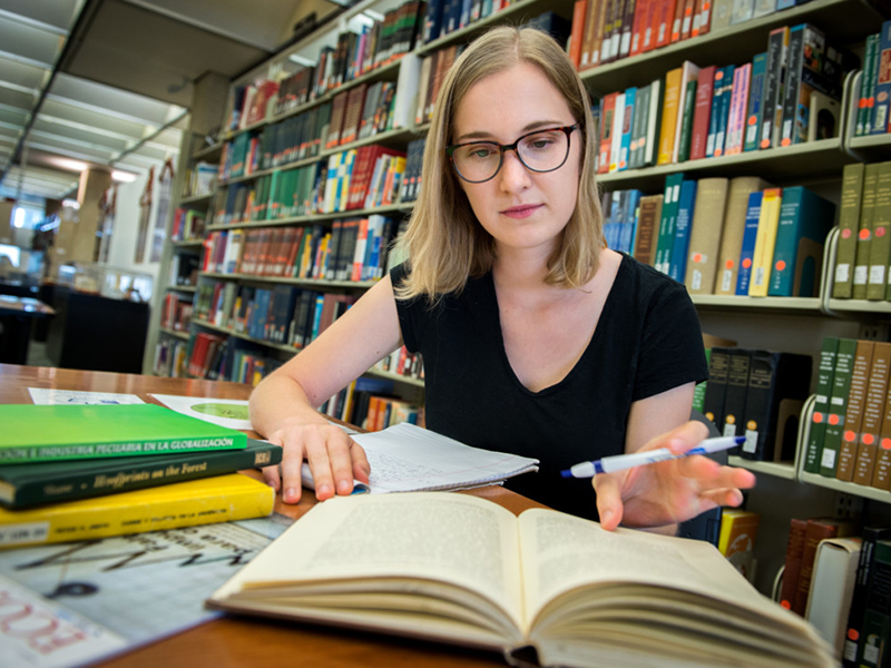student studying at library with open book